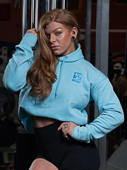 Shelby Guillaume, Mutant athlete, wearing the Sky Blue Mutant Thick Script Women's Gym Crop Hoodie while posing in the gym.